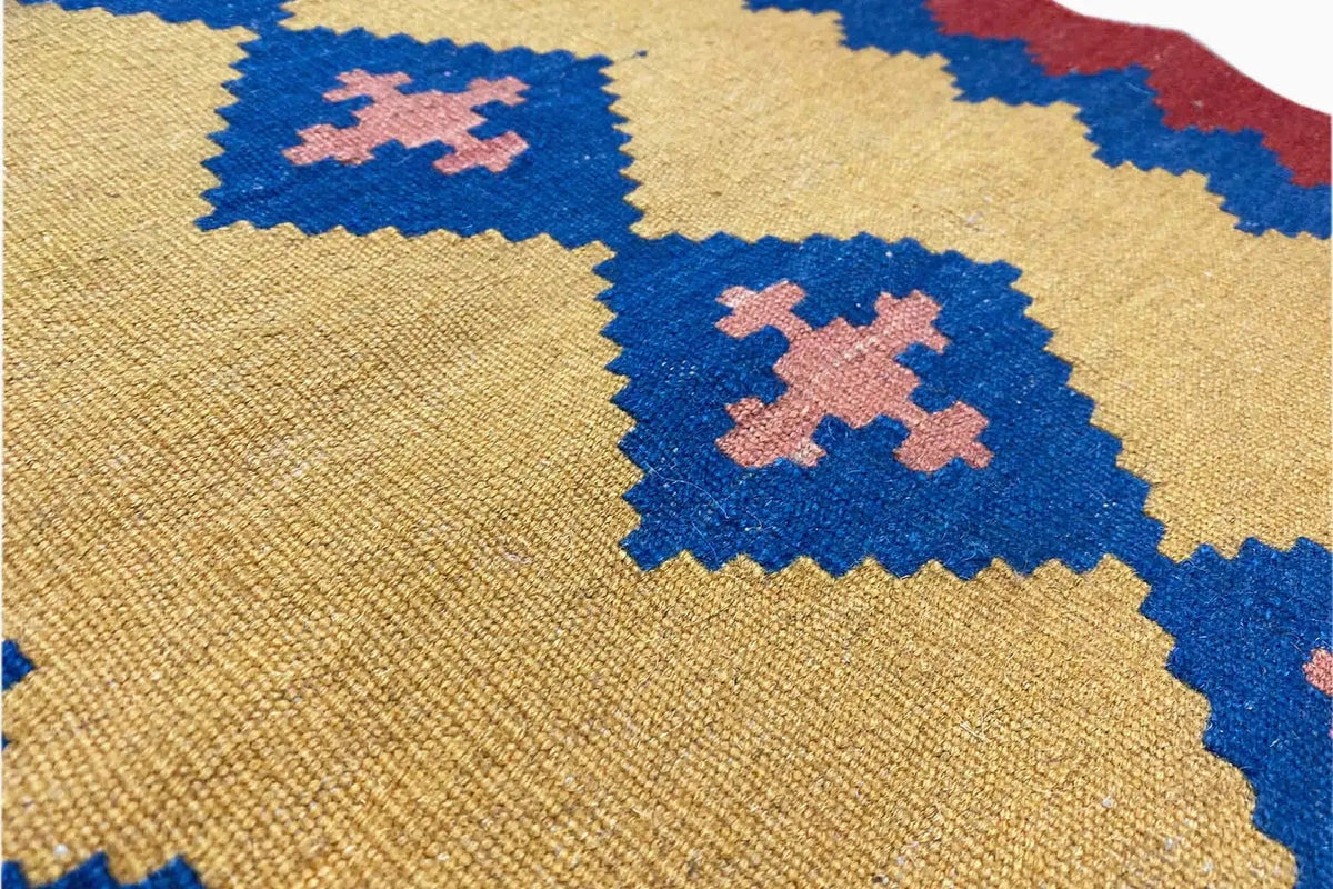 Kilim rug detail view: beige fabric with blue and pink diamonds