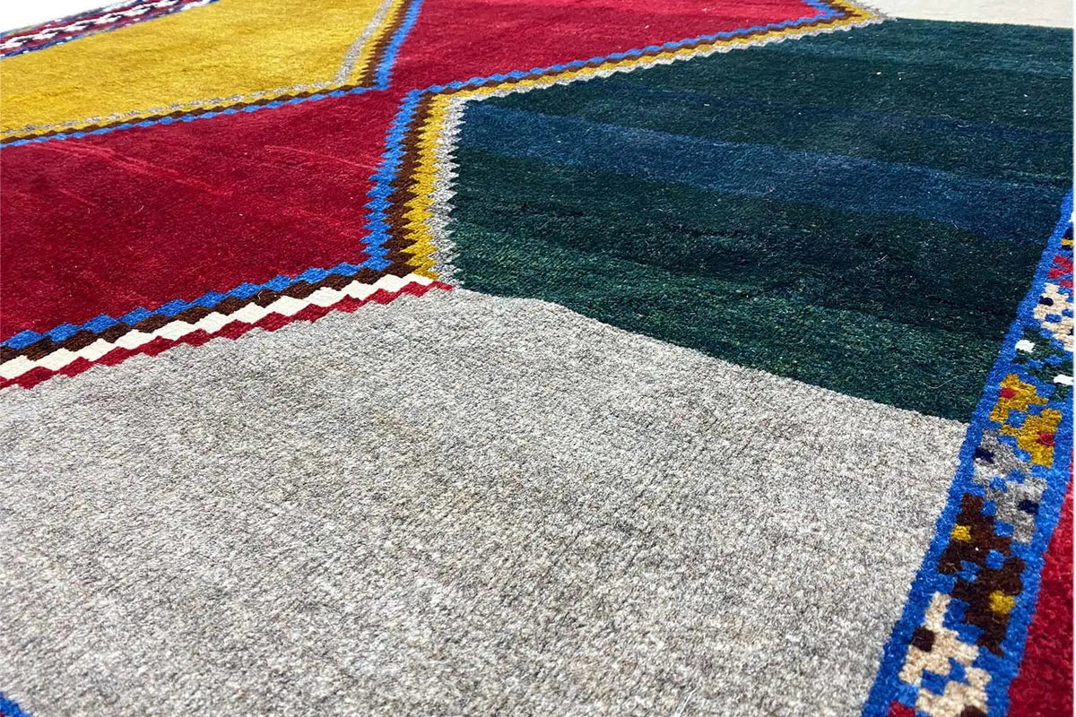Rug corner with ornamental fringe and colorful diamond sections, with a light pile