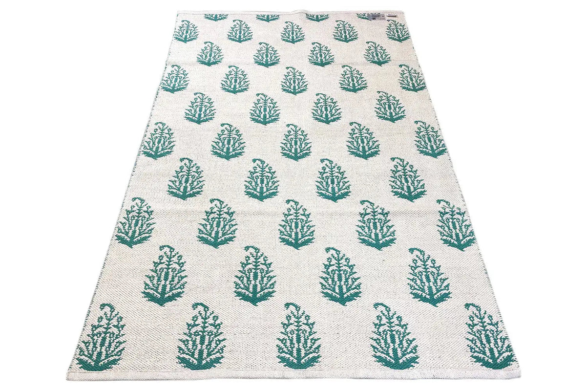 Modern kilim rug with a beige base and green tree pattern, laid flat