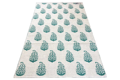 Modern kilim rug with a beige base and green tree pattern, laid flat