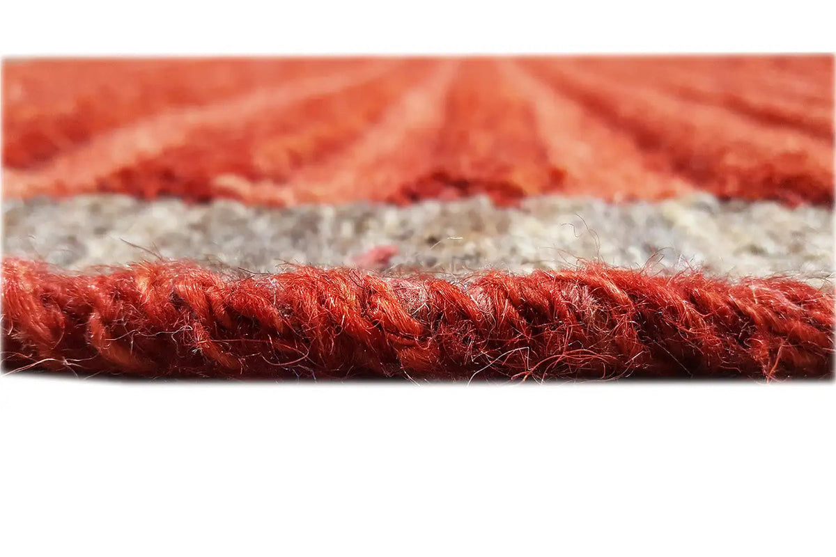 Carpet edge with a dense red fringe trim and a gray base underneath