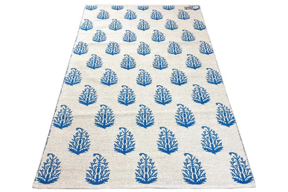 Cream-colored kilim rug with blue tree/branch motifs, an even grid.
