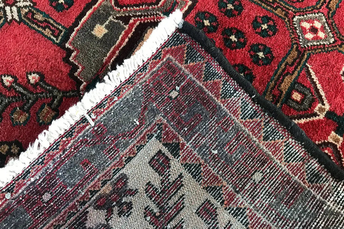Hamadan runner close-up: bound edge and gray diamond ornament in the red field