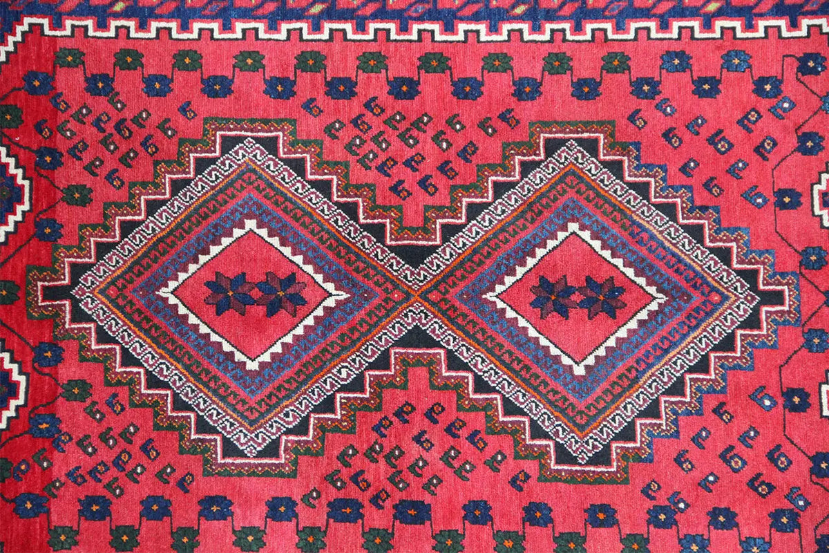 Oriental rug with a red ground, blue and white ornaments, corner medallions, and a decorative border