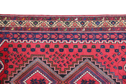 Carpet detail with a red background, blue vines, a zigzag pattern, and a decorative border