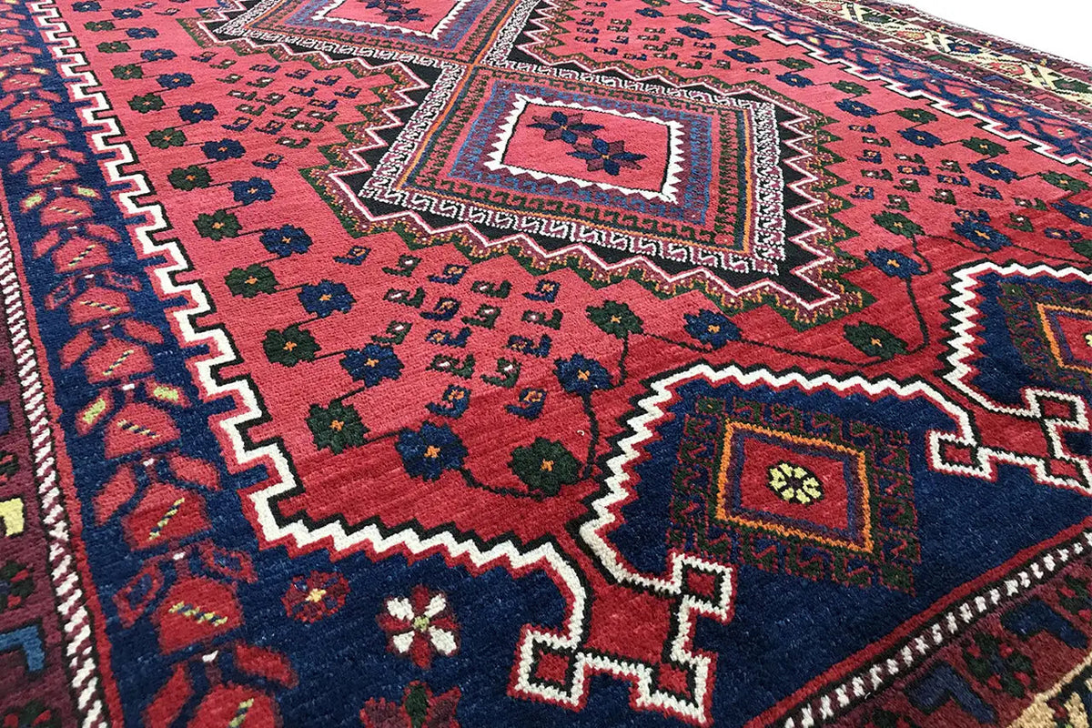 Close-up of carpet: red field, blue ornament in a quadrilateral, geometric patterns and border