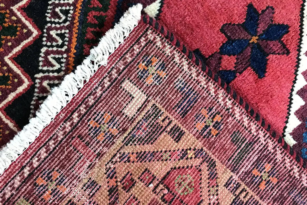 Carpet edge with white fringe and a dense pattern of red, blue, and yellow areas