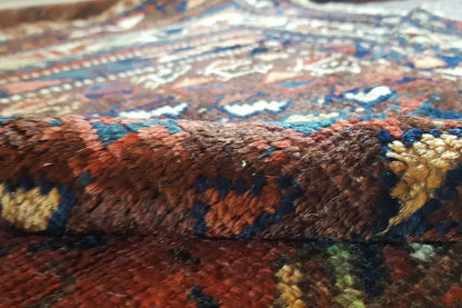 Carpet detail with red- and blue-toned threads and multicolored motifs in the pile