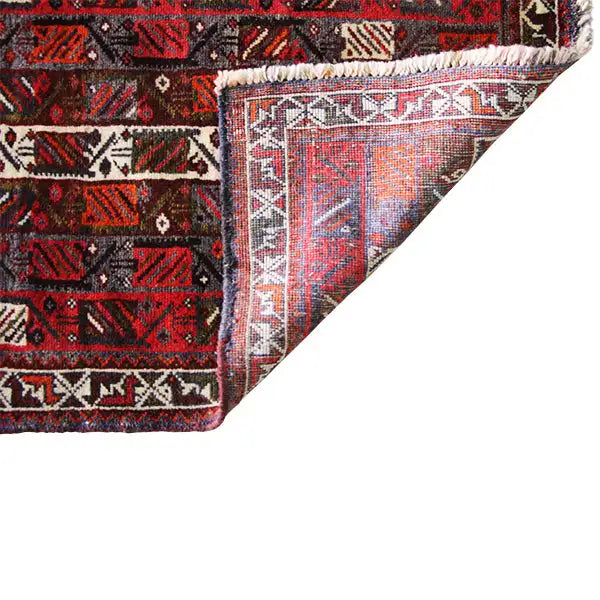 Close-up: carpet edge with beige decorative borders and fringes, red and black pattern