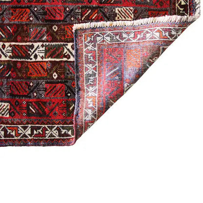 Close-up: carpet edge with beige decorative borders and fringes, red and black pattern