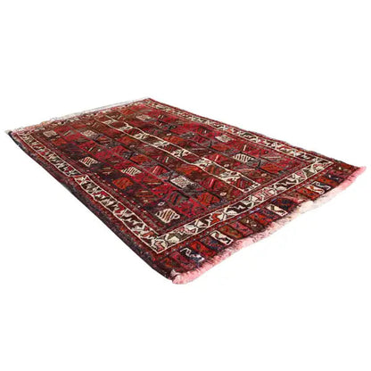Top view of a rug with a red and dark pattern, beige ornamental stripes, and fringes