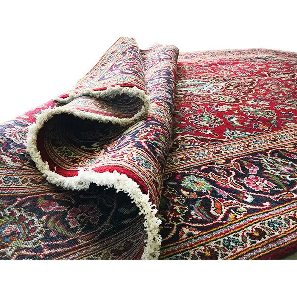 Keshan rug with a red background, ornaments, and a folded edge with fringes