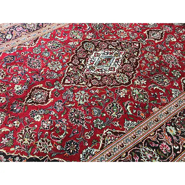 Red patterned rug with a dense floral design, border in beige and dark green