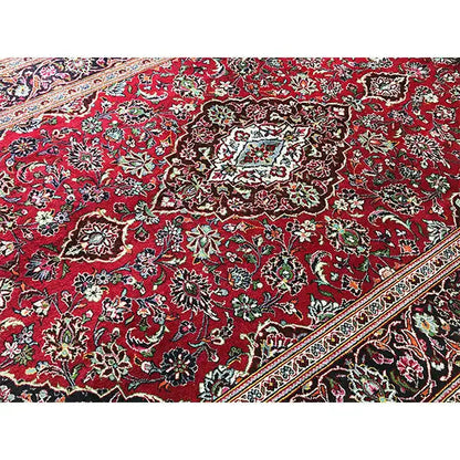 Red patterned rug with a dense floral design, border in beige and dark green