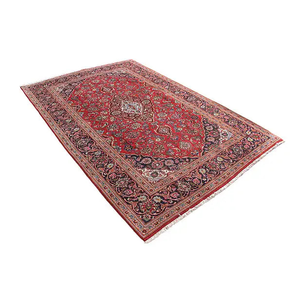 Red patterned rectangular rug with floral motifs, twisted view of the border