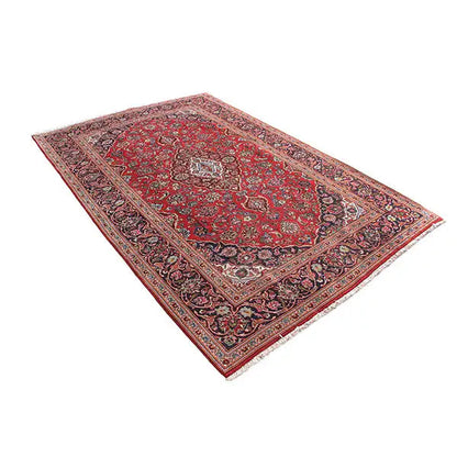Red patterned rectangular rug with floral motifs, twisted view of the border