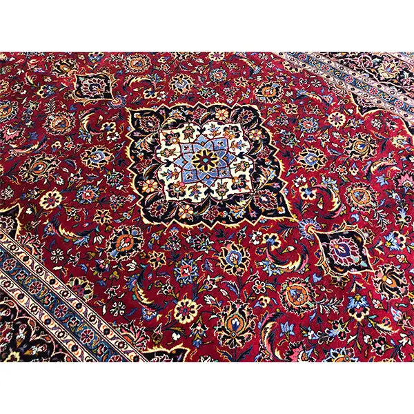 Keshan carpet detail: red field with delicate floral motifs and a multicolored border