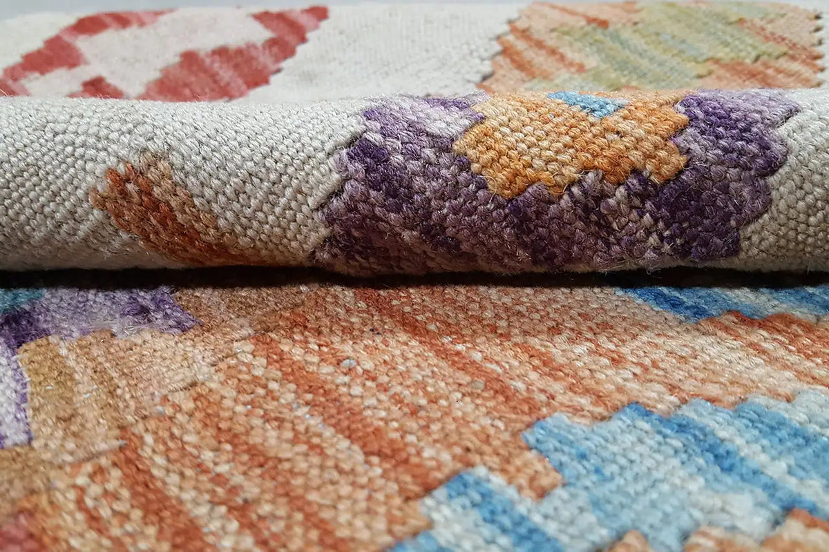 Kilim rug detail: coarsely woven texture with purple, orange, and blue patterns