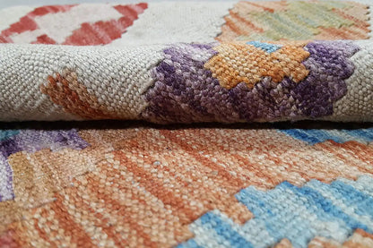 Kilim rug detail: coarsely woven texture with purple, orange, and blue patterns
