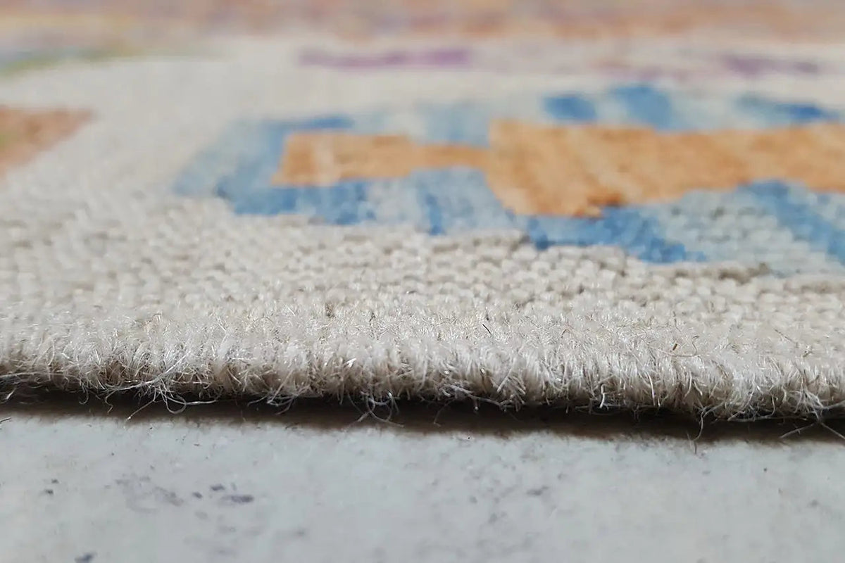 Close-up of a kilim rug at the edge with fringes and multicolored embroidered patterns