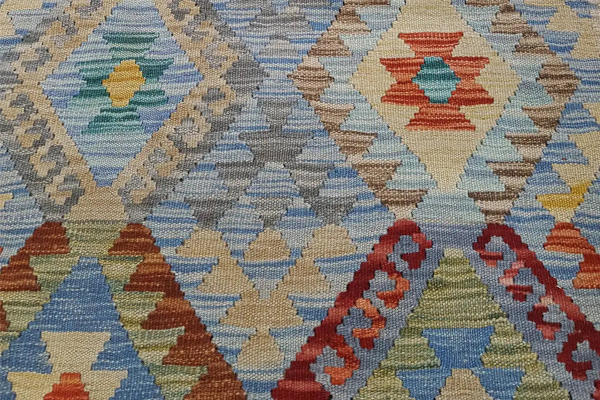 Close-up of a kilim rug with a geometric pattern in blue, red, and yellow.