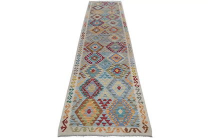 Kelim rug, narrow runner: white background with geometric patterns in blue, red and yellow.