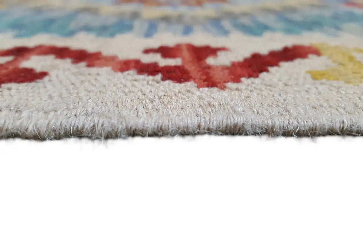 Rug edge with fringe: light-colored fabric with red patterns and a blue border.