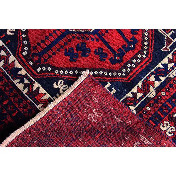 Close-up of a carpet edge with a red field, blue border pattern, and V-shaped ornaments