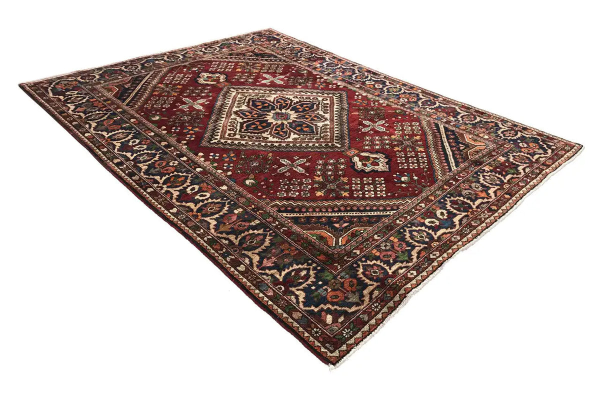 Rectangular Oriental rug with a red field pattern featuring a medallion and ornamental border