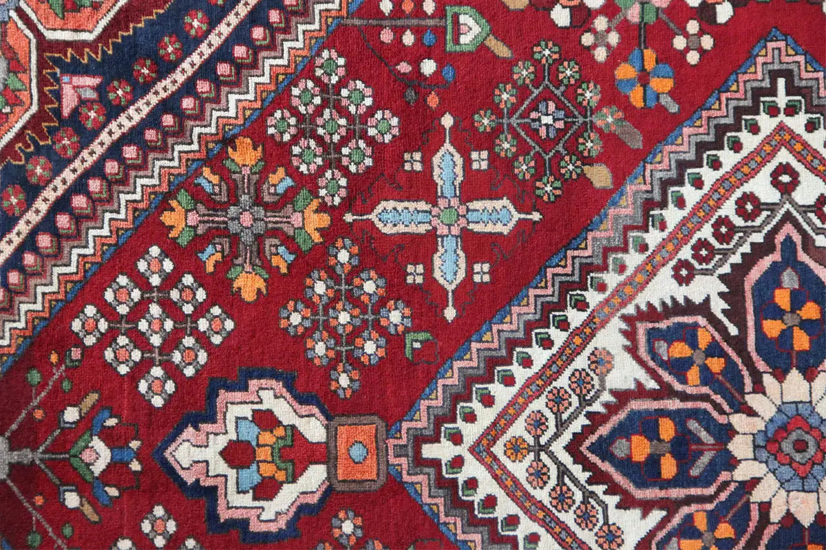 Detail of the Oriental rug with a red background, floral patterns, and geometric rows