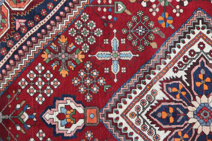 Detail of the Oriental rug with a red background, floral patterns, and geometric rows