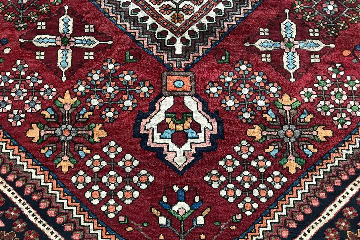 Rug corner: dark red background with cross and floral motifs, zigzag border