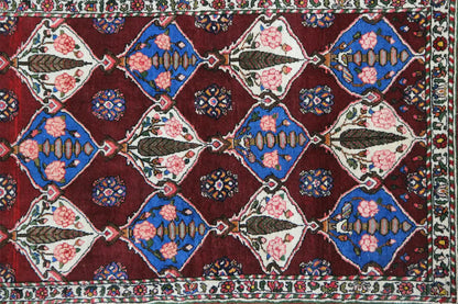 Bakhtiari rug: burgundy background with geometric motifs in blue, cream, and beige.