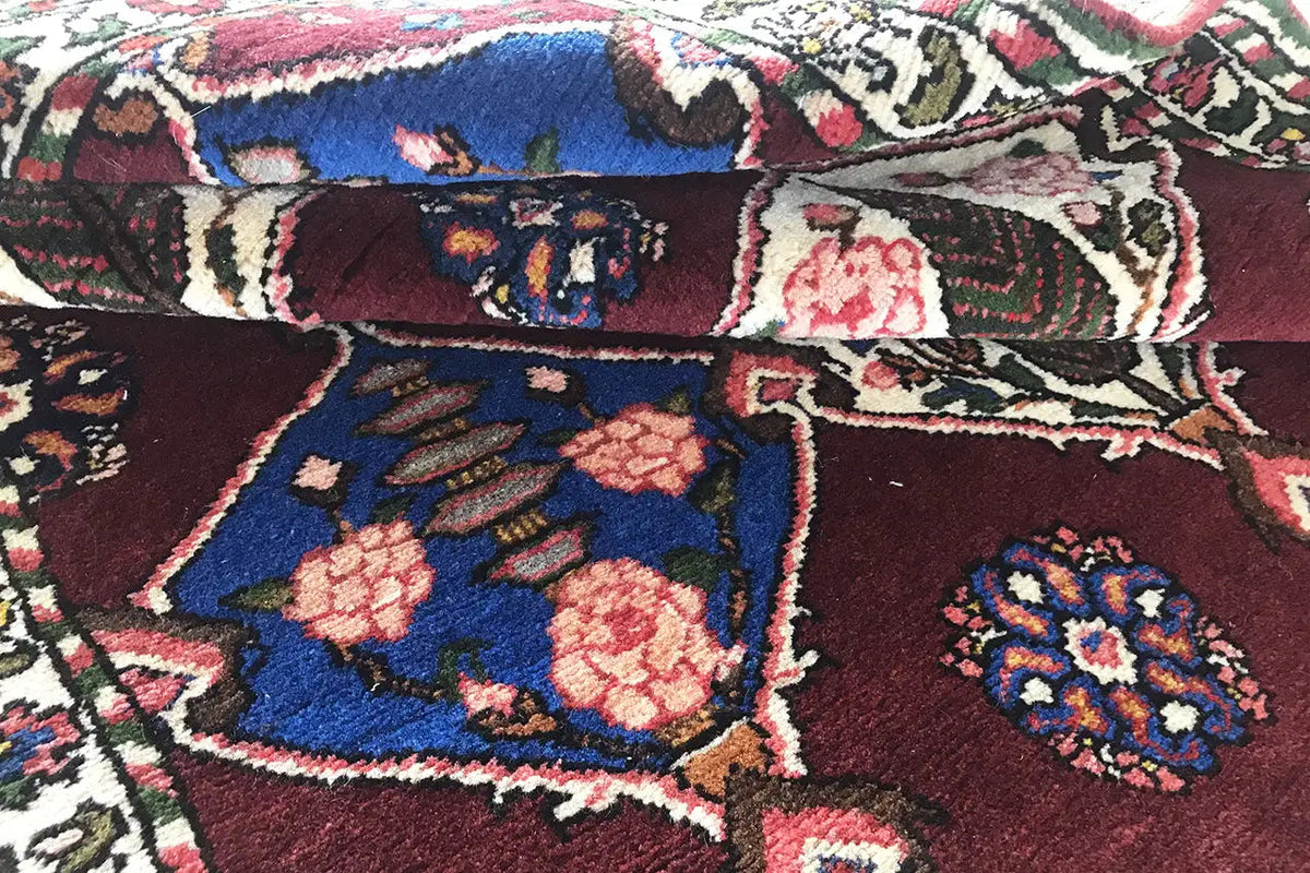Close-up of a Bakhtiari rug: blue-red pattern with vines, floral medallions, and border decoration.