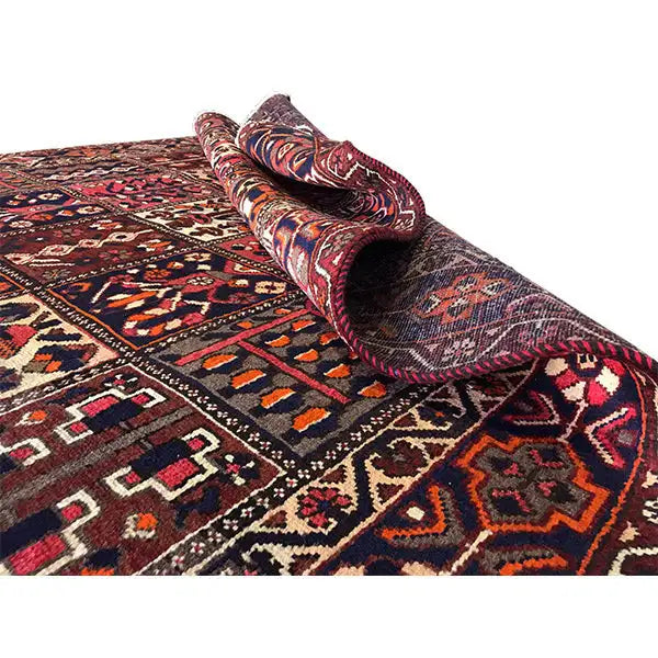 Rolled-up rug with visible pile; pattern in burgundy, blue, and beige