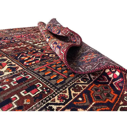 Rolled-up rug with visible pile; pattern in burgundy, blue, and beige