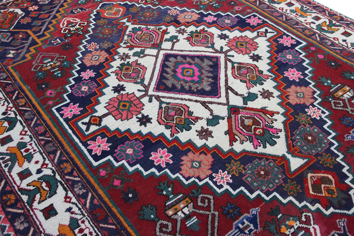 Close-up view of the oriental rug: high-contrast ornaments in red, blue, white, and purple