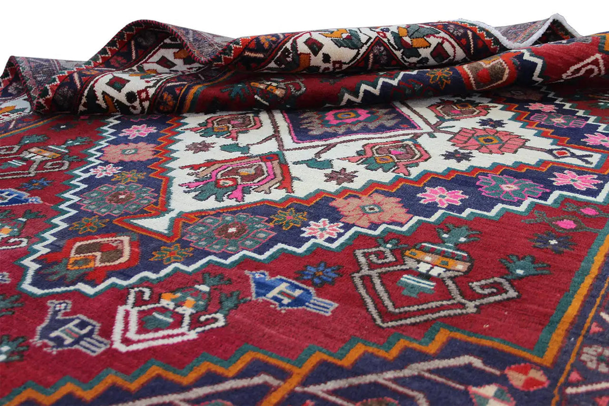 Oriental rug detail rolled up, colorful patterns in the central field, red, blue, white, pink
