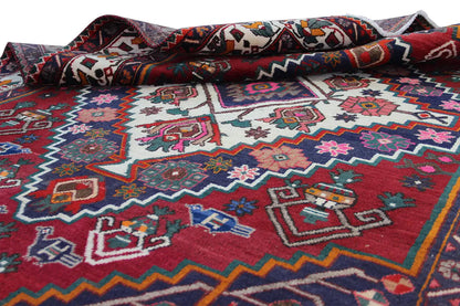 Oriental rug detail rolled up, colorful patterns in the central field, red, blue, white, pink