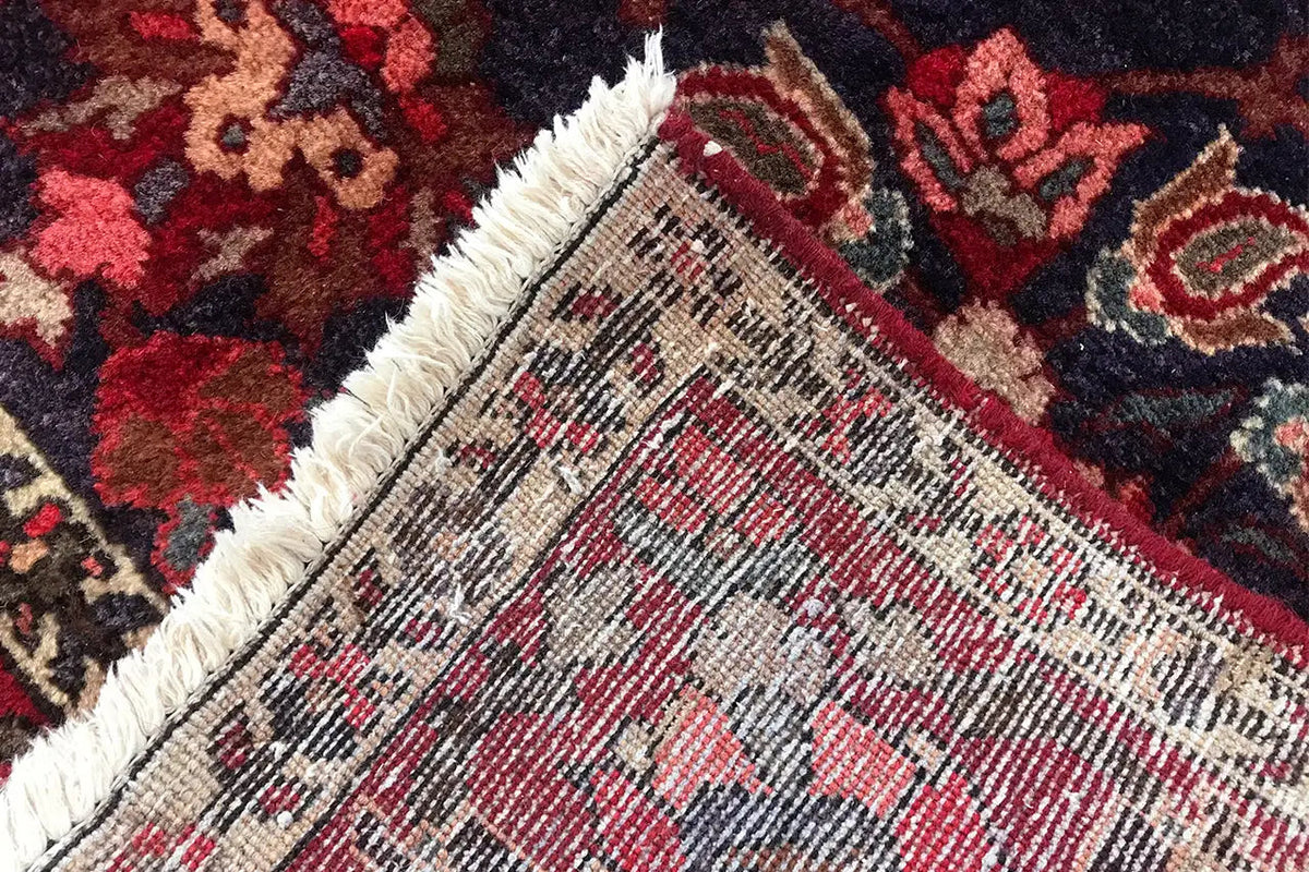 Rug edge with fringe, red ornament on a dark blue background and light border.