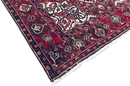 Rug corner with a dense pattern in red, blue, and white; textured pile weave