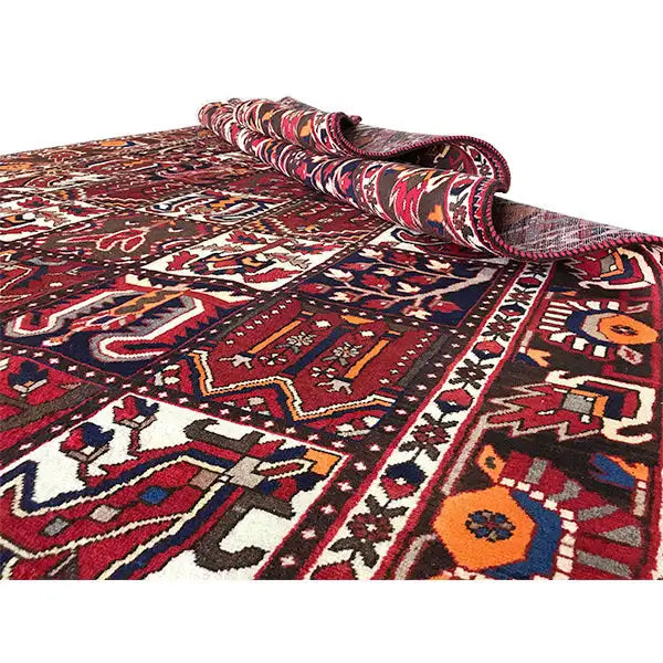 Bakhtiari rug with a rolled-up corner, burgundy color field, and intricate patterns