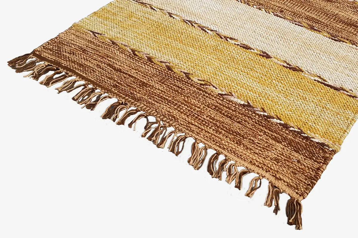 Corner of a kilim rug with fringes and stripes in brown, cream, and yellow