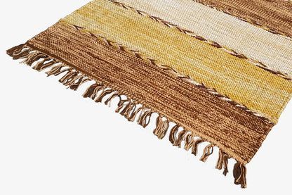 Corner of a kilim rug with fringes and stripes in brown, cream, and yellow