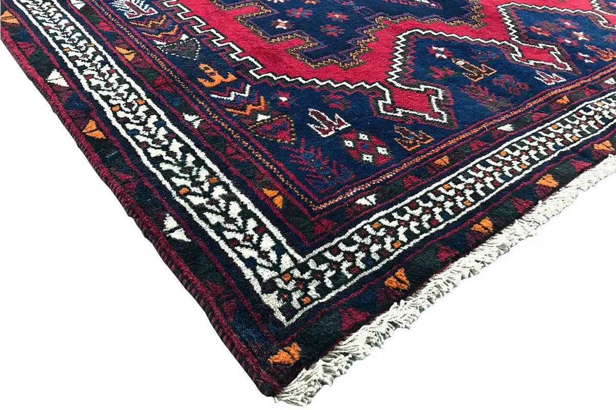 Corner view: dark blue rug with border and fringe along the edge