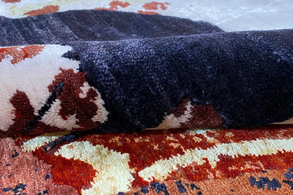 Rug with an abstract pattern in dark blue, red, and cream, with a visible pile texture