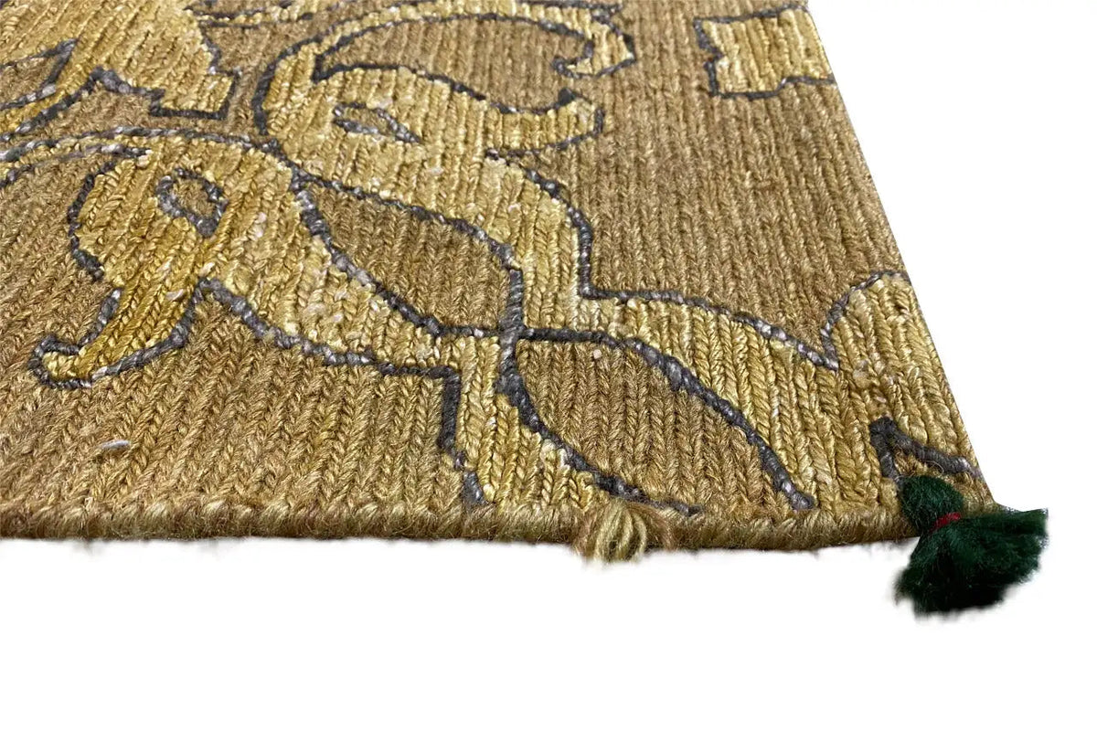 Close-up of designer rug: golden-brown pattern with a green fringe pom-pom