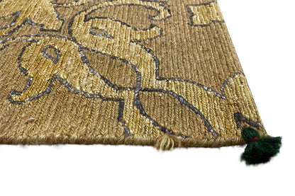 Close-up of designer rug: golden-brown pattern with a green fringe pom-pom