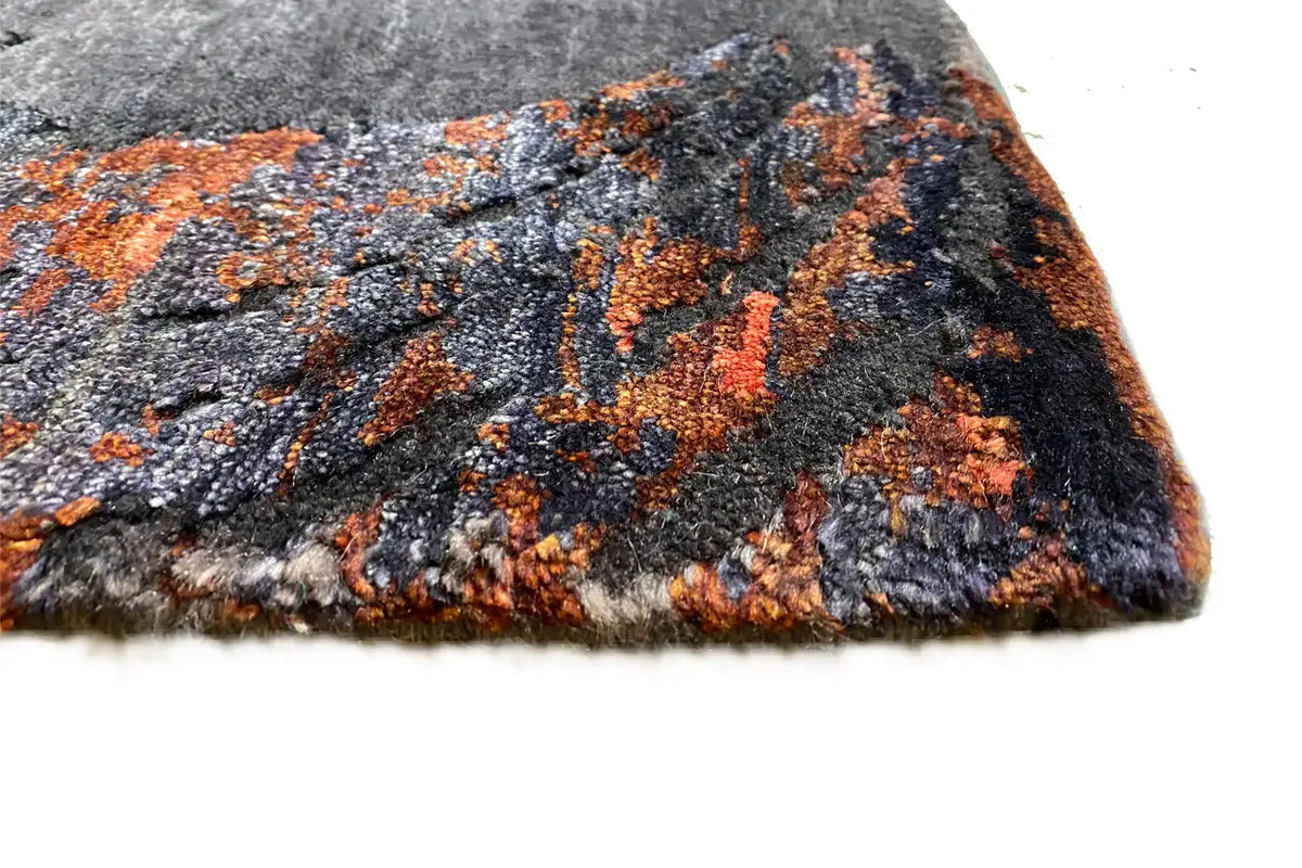 Designer rug with short pile in anthracite and orange, with a pattern and finished edges.