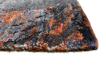 Designer rug with short pile in anthracite and orange, with a pattern and finished edges.